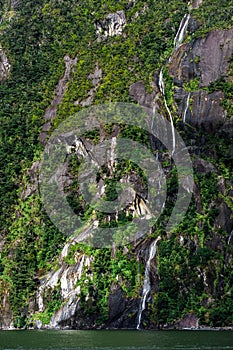 A stunning scene of nature with many waterfalls from the high mountain at Milford Sound, New Zealand. I