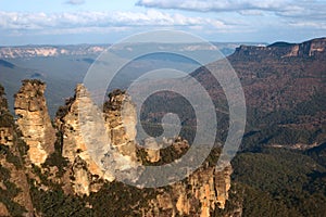 Stunning and scenic vista of Three Sisters outcrop, mountain ridge, plateau, forest covered valley in Blue Mountains National Park