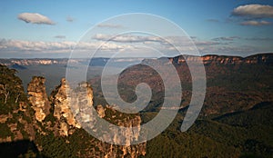 Stunning and scenic vista of Three Sisters outcrop, mountain ridge, plateau, forest covered valley in Blue Mountains National Park