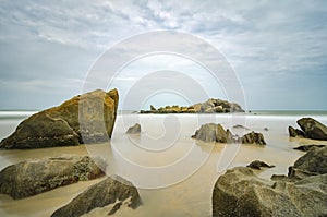 Stunning sea view of tropical beach. Wet Rock and crystal clear sea water with cloudy sky background