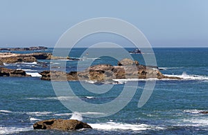 Stunning seascape, boat approaching rocky coast, Essaouira, Morocco