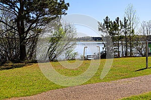 A stunning shot of the vast still lake water with lush green trees and plants on the banks of the lake