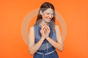 Stunning sly brunette woman in denim dress thinking over mysterious tricky plan, smirking