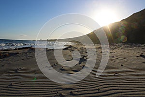 A stunning summer landscape at the beach at sunset with blue ocean water and waves rolling into the silky brown sands of the beach