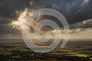 Stunning Summer landscape image of escarpment with dramatic storm clouds and sun beams streaming down