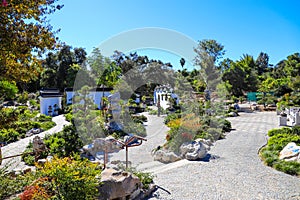 A stunning summer landscape in a Japanese garden with lush green trees and plants with brown buildings and clear blue sky