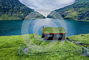 Stunning summer view of Saksun village with traditional turf-top house.