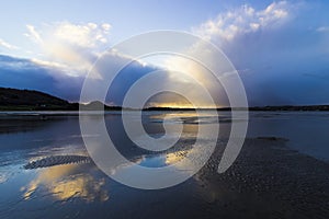 Stunning sundown storm cloud reflection off the water pooled surface of Red Wharf Bay, Anglesey