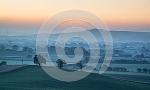 Stunning sunrise over fog layers in countryside landscape