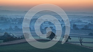 Stunning sunrise over fog layers in countryside landscape