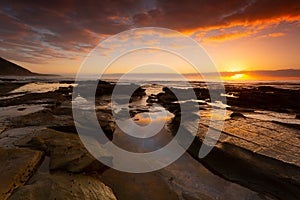 Stunning sunrise over the ocean, rocks and rock pools