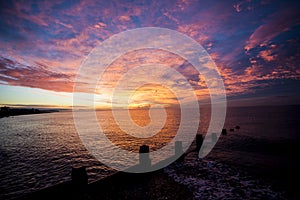 A stunning sunrise over the wood groynes on Bexhill beach in East Sussex, England