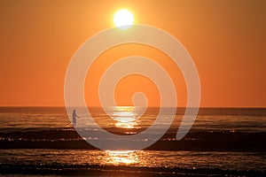 Stunning sunrise with single person paddle boarding over calm ocean waters