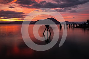 A stunning sunset across the flat calm waters just off the coast of Wrangell, Alaska, the sky appears to be on fire and the