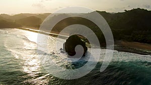 Stunning sunset over rock silhouettes on Asmara beach, Java, Indonesia, aerial