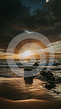 Stunning sunset over a rocky beach shoreline, with the glistening ocean waters in the background