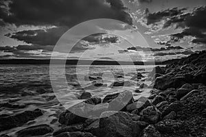 Sunset over the sea with the rocky sea coast in black and white