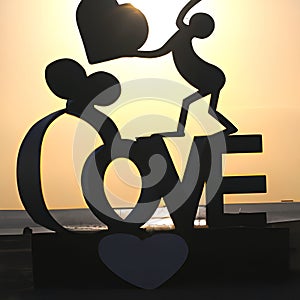 Stunning sunset silhouette with a figurine and the word 'Love' in a peaceful outdoor setting