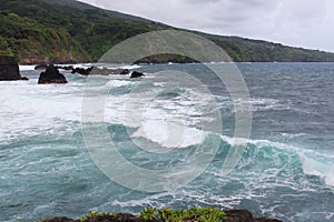 The stunning turquoise waters of the Pacific Ocean contrasted against the cliffside shoreline covered in lush vegetation in Maui