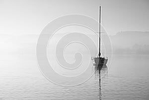 Stunning unplugged fine art landscape image of sailing yacht sitting still in calm lake water in Lake District during peaceful