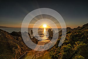 Stunning view of Camilo beach in Algarve with rocky cliffs engulfed by waves at bright sunrise