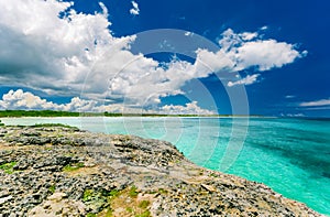 Stunning view from a cliff on tranquil turquoise ocean and beach against blue sky magic background