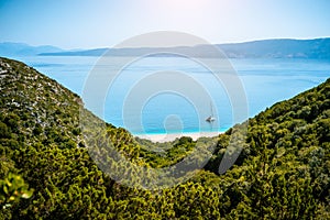 Stunning view of Fteri beach with white sailboat in hidden bay, Kefalonia, Greece. Surrounded by mediterranean