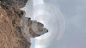 Stunning view of mountains and volcanic rocky hills in Gran Canaria, Spain. The sky is cloudy and hazy. In the valley between the