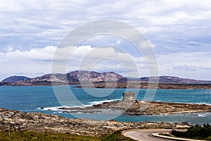 Stunning view on the old aragonese tower in La Pelosa Beach. Storm with beautifull waves with foam in Stintino, Sardinia, Italy