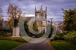 Stunning view of old Christ church and a statue in Brooke Park Derry against the cloudy sky
