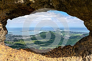 Stunning view through a rock window at the summit of famous Pali Puka hiking trail on the island of Oahu, Hawaii, USA. The dangero photo