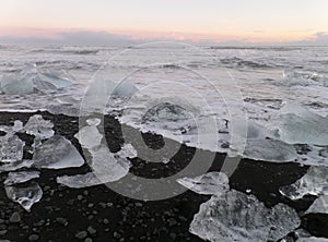 Stunning view of uncountable icebergs on the black sand beach under the sunset sky