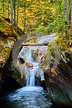 Stunning waterfall pouring through narrow mossy gorge in beautiful Vermont forest