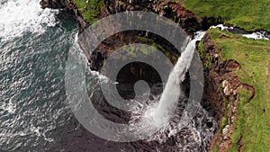 Stunning waterfall splashing from cliff aerial view. Mulafossur waterfall near Gasadalur Village at Faroe Islands