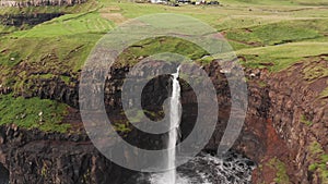 Stunning waterfall splashing from cliff aerial view. Mulafossur waterfall near Gasadalur Village at Faroe Islands