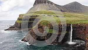 Stunning waterfall splashing from cliff aerial view. Mulafossur waterfall near Gasadalur Village at Faroe Islands