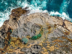 Stunning wide angle aerial drone view of the Mermaid Rock Pools and ocean waves at Matapouri Bay near Whangarei on the North Islan