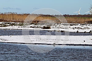 A stunning winter landscape shot at a nature reserve depicting snow covered fields surrounded by lakes