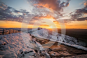 Stunning winter snowcapped mountain range hills summit sunrise. Mam Tor Derbyshire Peak District hill ridges hiking in winter snow