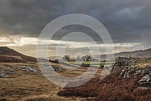 Stunning Winter sunset golden hour landscape image of view from Wast Water over countryside in Lake District towards the Western