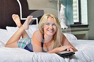 Stunning young blonde woman with e-reader in bed