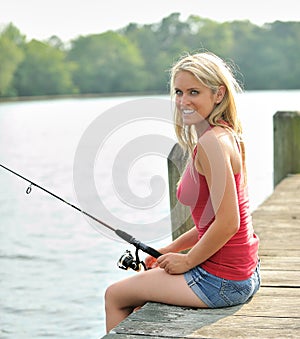 Stunning young blonde woman fishing from pier