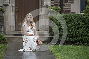 Stunning young blonde woman poses in white floral print dress