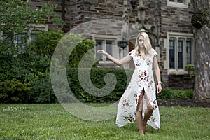 Stunning young blonde woman poses in white floral print dress