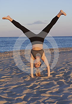 Stunning young blonde woman works out on beach at sunset