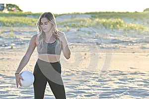 Stunning young blonde woman works out on beach at sunset