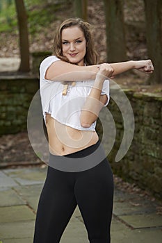 Stunning young fitness model poses outdoors of estate