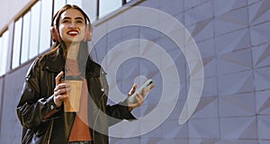 A stunning young woman walking down the street with a cup of coffee