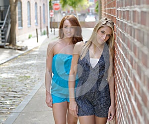 Stunning young women friends pose in rompers in city