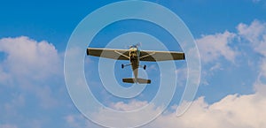 Stunt airplane flying in a blue sky with clouds, air transportation, hobby and sports
